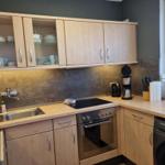 Küche mit Holzschränken, Spüle, Herd und Waschmaschine