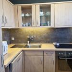 Küche mit Holzschränken, Spüle, Herd und Backofen.