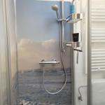 Duschkabine mit Meeresmotivwand und Chromarmaturen.