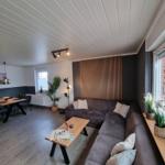 Wohn- und Essbereich mit Sofa, Tisch und Pflanzen.