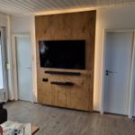Wohnzimmer mit TV an Holzwand, Tür und Fenster.