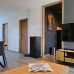 Wohn- und Essbereich mit Fernseher, Tisch und Stühlen sowie Tür zu einem anderen Raum.