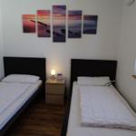 Zwei Einzelbetten mit Nachttisch und Wandbildern.