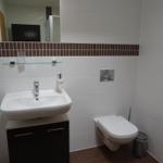 Badezimmer mit Waschbecken, Toilette und Spiegel.