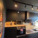 Küche mit Herd, Spüle und Mikrowelle. Dunkle Wände und Holzoberflächen.