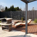 Terrasse mit Grill, Liegestühlen und Pool unter Pavillon.