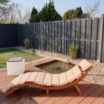 Holzliege mit Kissen neben einem kleinen Pool auf einer Terrasse.