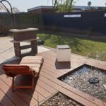 Terrasse mit Liege, Brunnen und Garten. Holzdecke und Rasenfläche.