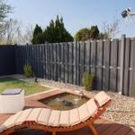 Hinterhof mit Liegestuhl, Brunnen und Holzterrasse.