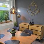 Esszimmer mit Holztisch, Stühlen und Pflanzen. Wanddekoration und Fensterblick.