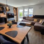 Wohnzimmer mit Essbereich, Sofa und Küchenbereich. Holztisch und -stühle.