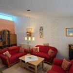Wohnzimmer mit zwei roten Sofas, Couchtisch und Holzmöbeln.