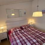 Schlafzimmer mit Bett, Nachttischen und Spiegel an der Wand.