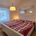 Schlafzimmer mit Doppelbett, zwei Nachttischen und Fenster mit Vorhängen.