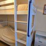 Zimmer mit Doppelstockbett, Nachttisch und Wandbild.