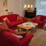 Ein Wohnzimmer mit roten Sesseln, einem Holztisch und einem Fernseher.