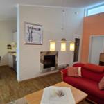 Wohnzimmer mit rotem Sofa, Kamin und Essbereich im Hintergrund.