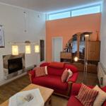 Wohnzimmer mit rotem Sofa, Kamin und Holzboden.