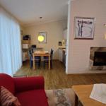 Wohnzimmer mit Kamin, Essbereich und Küche. Rote Sofas und Holzboden.