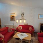 Wohnzimmer mit zwei roten Sofas, Holztisch und Wandbildern.