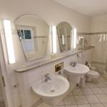 Badezimmer mit Dusche, zwei Waschbecken und Spiegeln