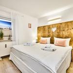 Schlafzimmer mit Holzwand, Bett und Fenster mit Meerblick.