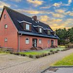 Rotes Backsteinhaus mit Dachgauben und gepflastertem Weg.