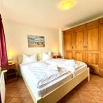 Schlafzimmer mit Doppelbett, Holzschrank und Nachttischen.