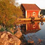 Rotes Bootshaus am See mit Steg und Rettungsring.