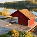 Rotes Bootshaus am See mit Holzsteg und zwei Booten.