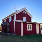 Rotes Holzhaus mit weißem Rahmen und Fenstern am See
