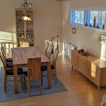 Esszimmer mit Holztisch, Stühlen und Sideboard. Fenster mit Blick auf Schnee.