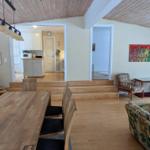 Essbereich mit Holztisch, Wohnzimmer mit Sofa und Stühlen, Küche im Hintergrund.