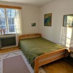 Schlafzimmer mit Holzbett, Fenster und Wandbildern.