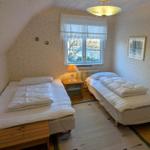 Zwei Betten, Fenster, Nachttisch, Decken und Wandtapete.