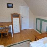 Schlafzimmer mit Holzboden, Schreibtisch, Bett und Kleiderschrank.