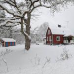 Rotes Haus mit Schneebedecktem Garten und kleinem Nebengebäude.