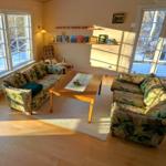 Wohnzimmer mit zwei Sofas, Tisch und Fenstern zum Ausblick.