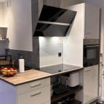 Moderne Küche mit Kochfeld, Backofen und Holz-Arbeitsplatte.