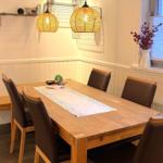 Esstisch mit sechs Stühlen, zwei Hängelampen und Fenster mit Blenden.