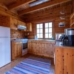 Küche mit Holzelementen, Kühlschrank, Herd und Fenster.