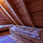 Zwei Betten in einem Holzhaus mit Dachschrägen und Fenster