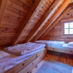 Zimmer mit zwei Betten, Holzwand und Dachfenster.