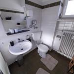 Badezimmer mit Waschbecken, Toilette und Fenster.