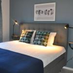 Schlafzimmer mit Bett, Wandlampen und Bild an der Wand.