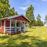 Rotes Holzhaus mit Veranda und Garten. Blick auf den See.