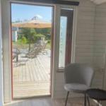 Durch die Glastür ist eine Terrasse mit Sonnenschirm und Sitzgelegenheiten zu sehen.