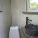 Badezimmer mit Toilette, Waschbecken und Fenster.