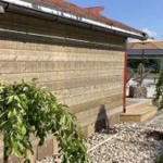 Holzwand, Terrasse mit Sonnenschirm und Gartenbereich
