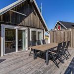 Terrasse mit Tisch und Stühlen vor einem Holzhaus mit Schiebetüren.